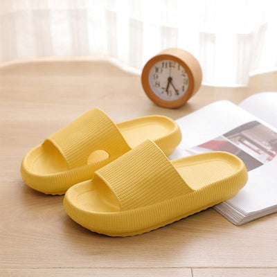 Yellow bathroom slippers on a wooden floor with a clock in the background.