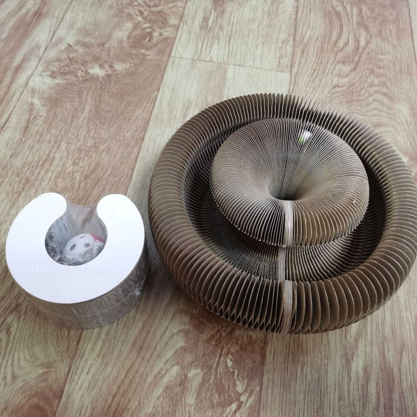 Corrugated and foldable cat paper nest on wooden floor for cat play and comfort