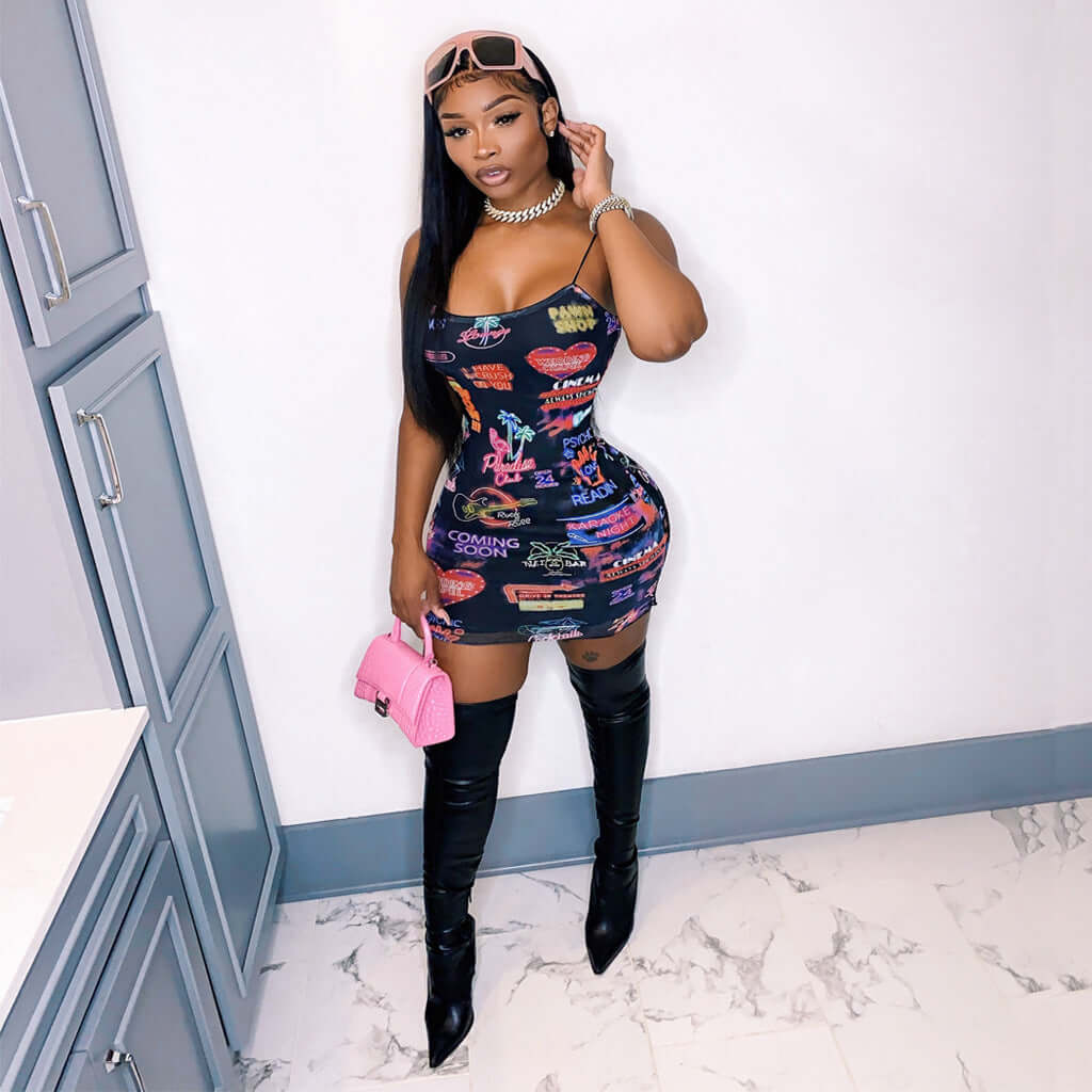Woman wearing a collage splicing printed sling bodycon mini dress with colorful patterns, paired with black thigh-high boots and holding a pink handbag.
