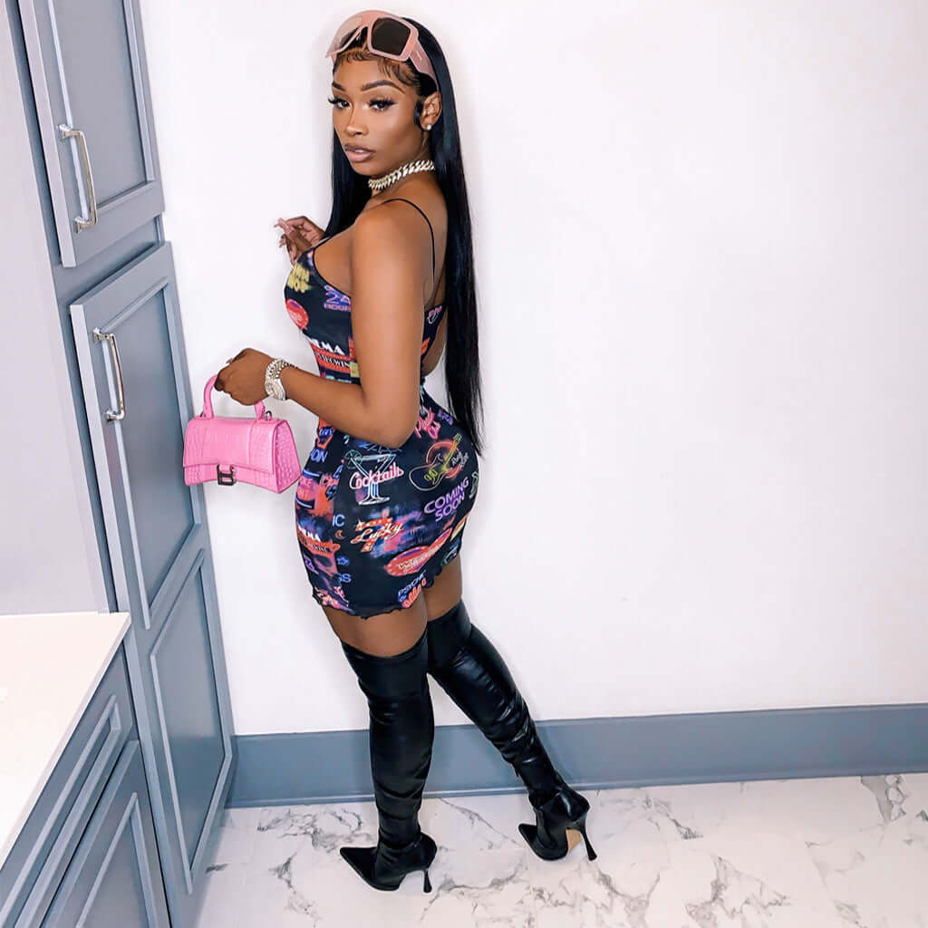 woman wearing collage splicing printed sling bodycon mini dress with thigh-high boots and pink handbag