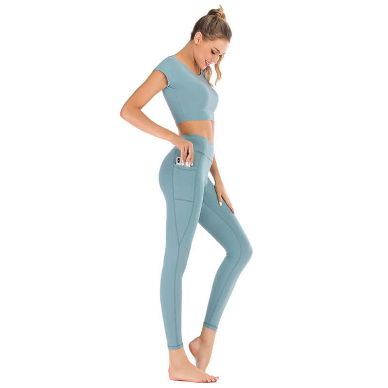 Woman wearing light blue pocket yoga clothes suit with short sleeves and leggings, holding a phone, available in sizes S, M, L, XL