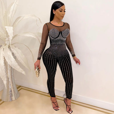 Woman wearing black see-through mid waist jumpsuit with long sleeves and sparkling diamond accents