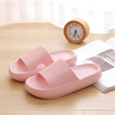 Pink couple bathroom slippers on a wooden surface with a clock in the background.