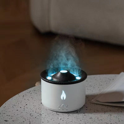 White ultrasonic essential oil humidifier with blue flame lighting and mist on a table
