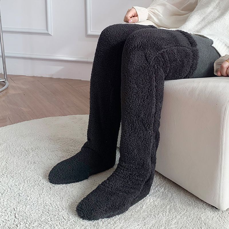 Over knee high fuzzy socks in black for winter warmth, suitable for home lounging or sleeping.