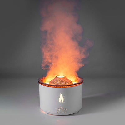 White ultrasonic essential oil humidifier with glowing orange flame and mist smoke effect in a dark setting