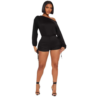 Woman wearing black off-shoulder long sleeve jumpsuit with pleating design and diagonal collar