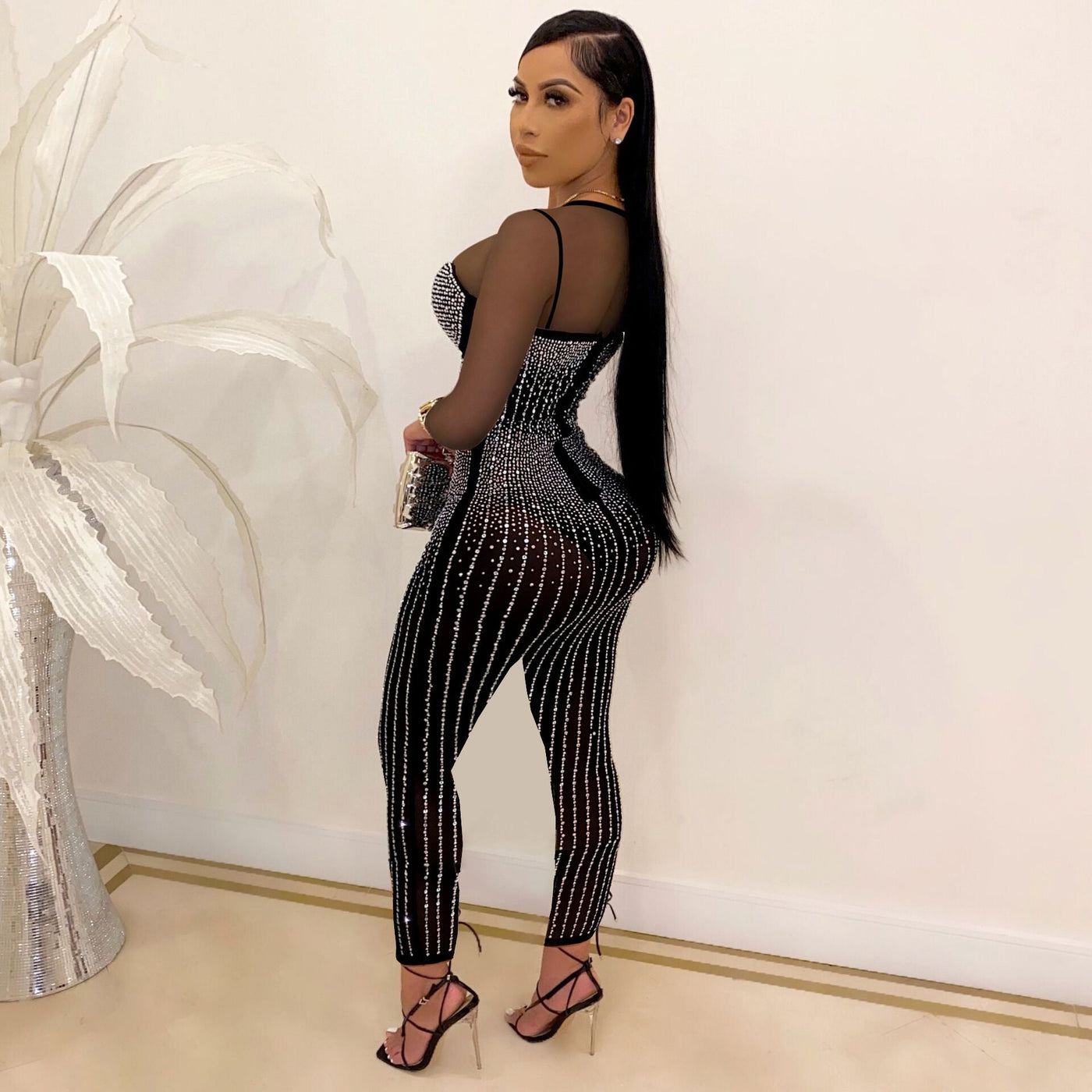 woman wearing mid waist see-through long sleeve mesh jumpsuit with diamond accents and pencil pants heels