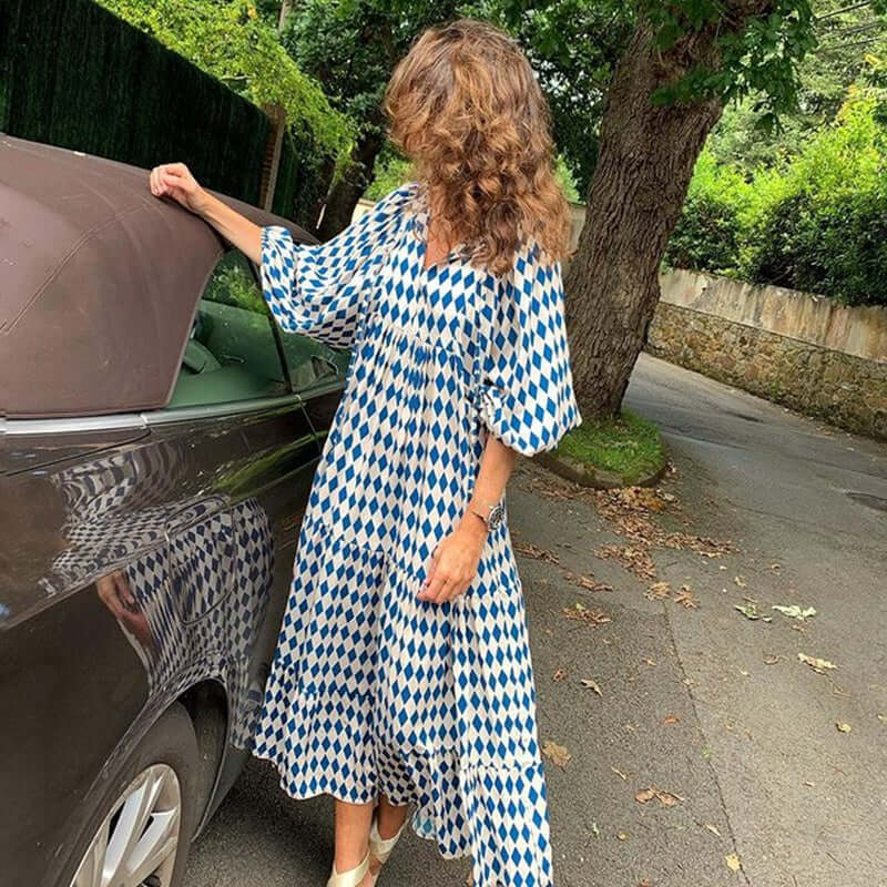 Woman wearing a British style vintage bohemian midi dress with blue and white diamond pattern outdoors near a car