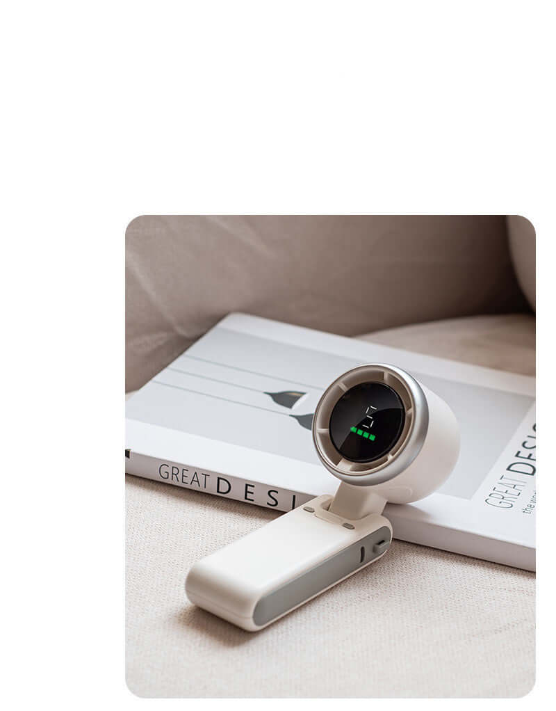 Portable white folding neck fan with Type-C input interface and digital display on beige surface next to book