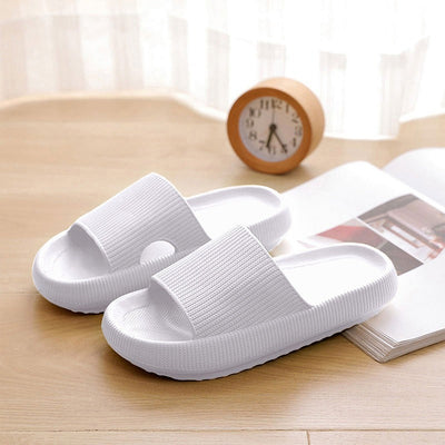 Home household bathroom slippers in white on wooden surface.